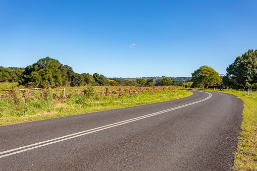 Rural country road under sunny clear blue sky