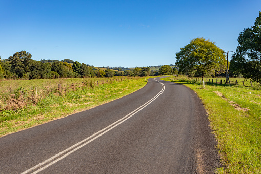 Rural country road under sunny clear blue sky