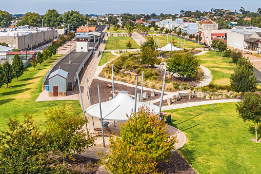 Old Mount Gambier railway station and shunting yard converted into open space in town centre: new vibrant recreation area blended with history coexisting with industry and retail shopping precinct. Heritage, sunshades, landscaped gardens, paved path, sculptures.