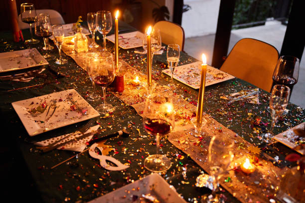 Candlelit dining table covered in sparkling confetti during a New Year's Eve party stock photo