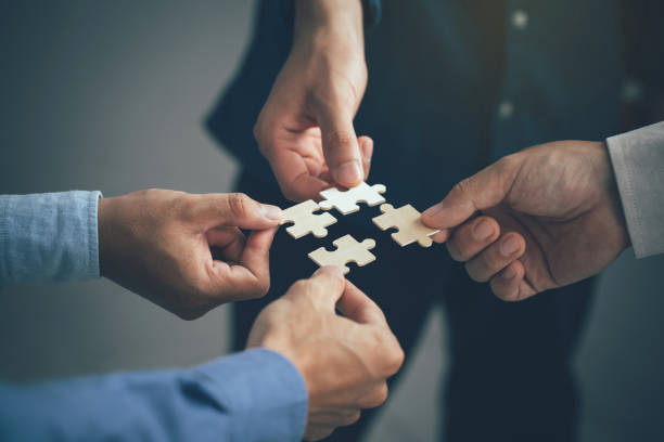 チームワークとパートナーシップの概念。オフィスでパズルのピースを手がつなぎ合わせます。ジグソーパズルチームをまとめるビジネスマン。チャリティー、ボランティア。団結、チーム� - human hand puzzle togetherness connection ストックフォトと画像