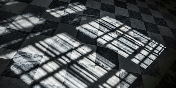 Shadow on tiled floor from sunlight through window frame. Abstract geometric pattern and background.