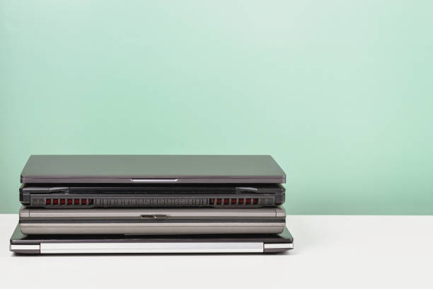 istock Pile of old used laptop computers for recycling on white table. Planned obsolescence, e-waste, electronic waste for reuse and recycle concept 1400570428