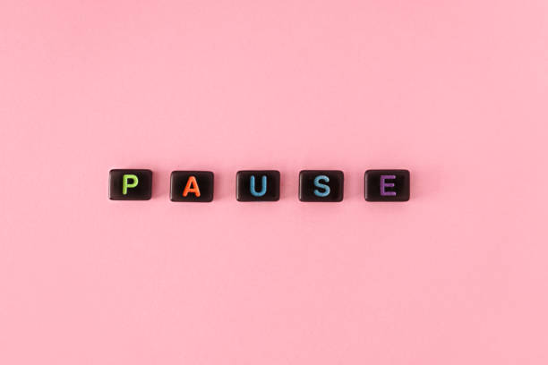 istock Pause button concept. Black beads on pink background making word 1400573707