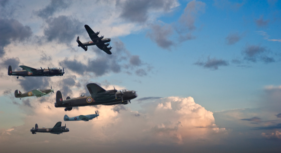 Flight formation of Battle of Britain World War Two consisting of Lancaster bomber, Spitfire and hurricane airplanes on beautiful sunset sky background