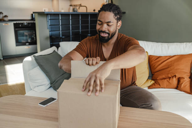 istock Young man unpacking the box in which his online order has arrived 1400582817