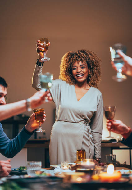 donna felice che brinda con un bicchiere di vino durante una cena - champagne celebration glass black foto e immagini stock