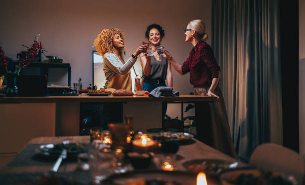 tres mujeres brindando con una copa de vino durante la preparación de la cena - party host fotografías e imágenes de stock