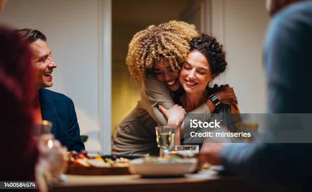 Two Friends Hugging During A Dinner Celebration Stock Photo - Download Image Now - Family, Friendship, Dinner
