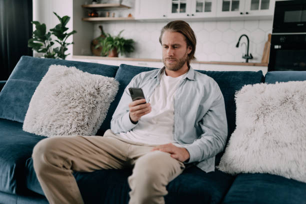 istock A man types text on his phone and smiles while sitting at home on the couch. chatting with loved ones 1400586577