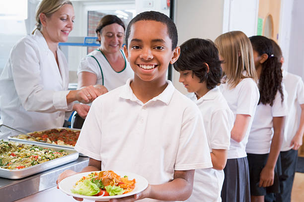 schoolboy holding plate of lunch in school cafeteria - schoollunch stockfoto's en -beelden