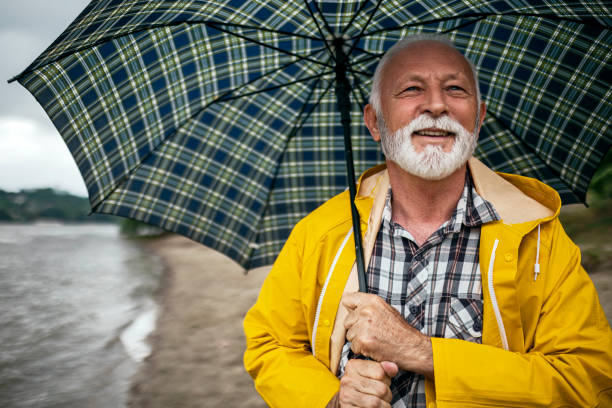 istock Senior man walking on a raining day along river 1400586910