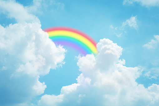 Rainbow and clouds against bright blue sky
