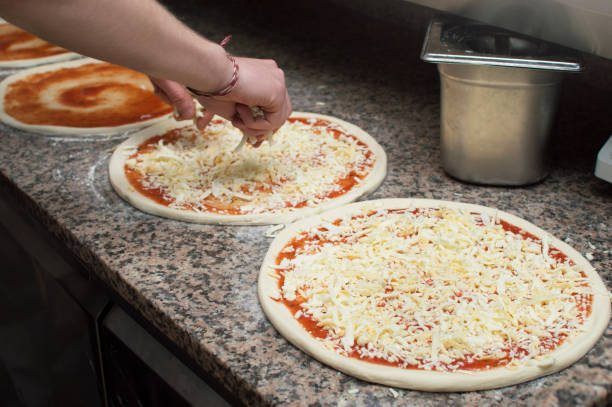 istock Cook in the kitchen putting the ingredients on the pizza. Pizza concept. 1400592407