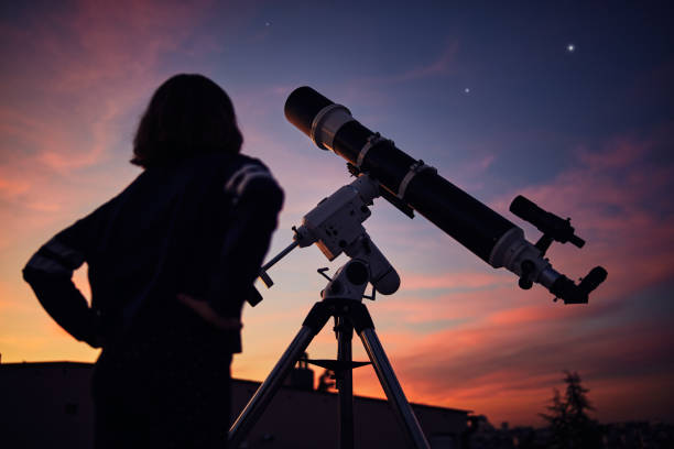 istock Girl with astronomical telescope stargazing under twilight sky. 1400599829