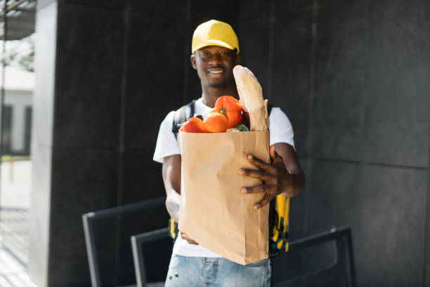 istock African American courier standing with a package with fresh food from the store. 1400603131