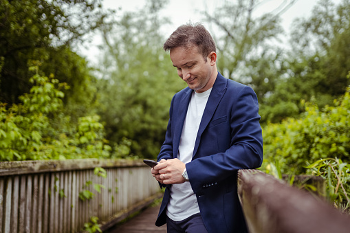 Business Man using mobile phone in nature and taking photos