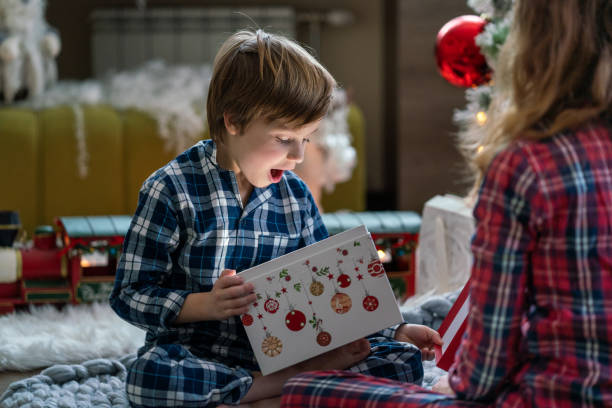Surprised little boy opening Christmas present Surprised little boy opening Christmas present whit her sister at home unwrapping stock pictures, royalty-free photos & images