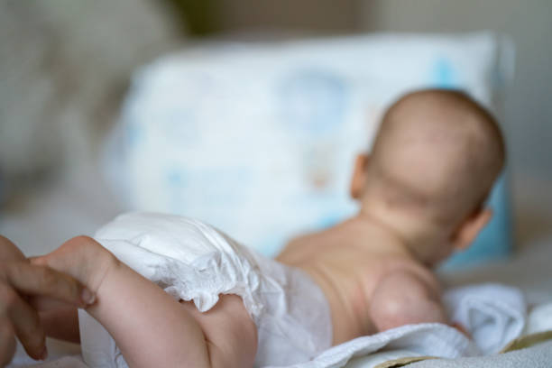 Baby legs in diaper on bed lying on front