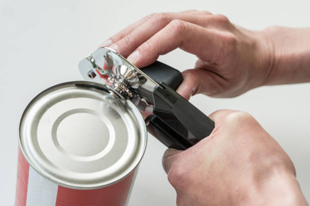 istock Hands opening a can in a kitchen with a tin opener. 1400603777