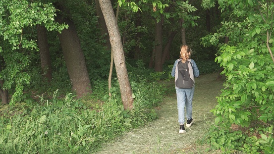 A girl of nine years old with a hiking bag on her back travels through the forest. Hiking. High quality photo