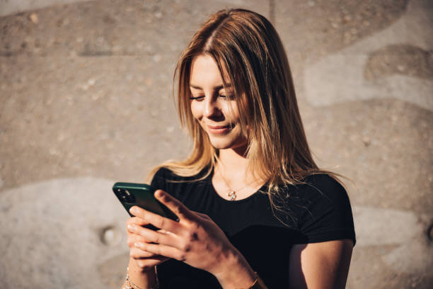 Happy Smiling Young Fashionable Woman Using Her Mobile Phone For Texting Massage stock photo