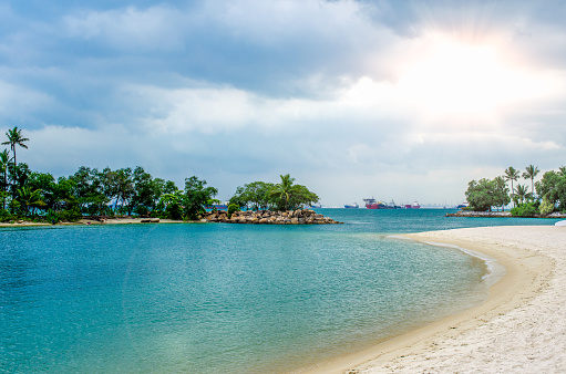 Tropical beach with sand, summer holiday background. Beautiful tropical island with palm trees. Palawan beach at Sentosa Island in Singapore.