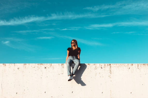istock Young Woman Sitting on Concrete Wall 1400605012