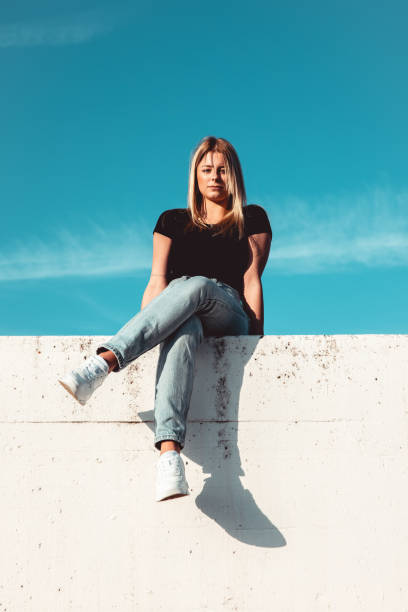 istock Serious Looking Young Woman Sitting on Concrete Wall 1400605014