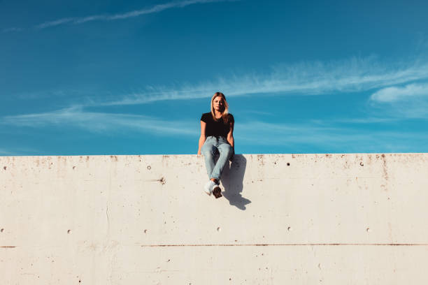 istock Young Woman Sitting on Concrete Wall 1400605335