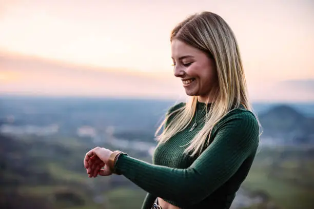 Photo of Young Woman Outdoors Checking Modern Smart Watch After Walk