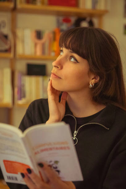 istock Young woman reading a book and thinking 1400609120