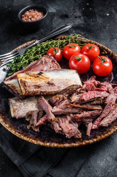 istock Smoked and grilled beef short ribs in rustic plate with herbs. Black background. Top view 1400610615