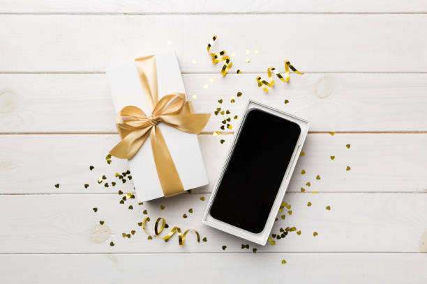 istock Opened gift box with gold ribbon and smartphone on color background, top view. Blank open box packaging mockup , Template for your design - branding mockup 1400611667