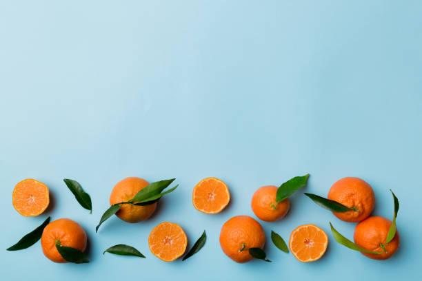 istock Many fresh ripe mandarin with green leaves on colored background, top view, space for text 1400611715