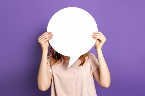 istock Student with blank white speech bubble isolated on purple studio background. copy space. woman holding a round information piece of paper dialog. 1400612122