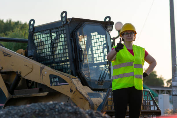 istock Cheerful female excavator operator on construction site. Woman construction apprentice learning to drive heavy equipment 1400613254