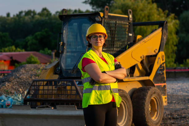 istock Cheerful female excavator operator on construction site. Woman construction apprentice learning to drive heavy equipment 1400613260
