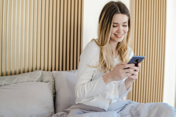 istock Young woman uses a mobile phone in bed while waking up 1400613271