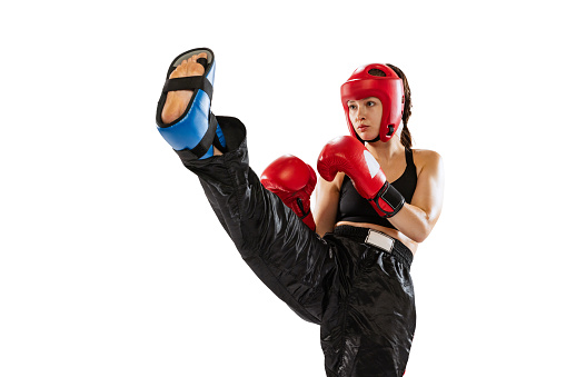 Close-up female boxer in boxing gloves and helmet training isolated on white background. Sport, competition, hobby, results, success concept. Sportive woman practicing in boxing. Copy space for ad