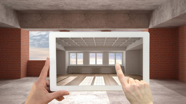 istock Augmented reality concept. Hand holding tablet with AR application used to simulate furniture and design products in an interior construction site, empty interior with parquet floor 1400617043
