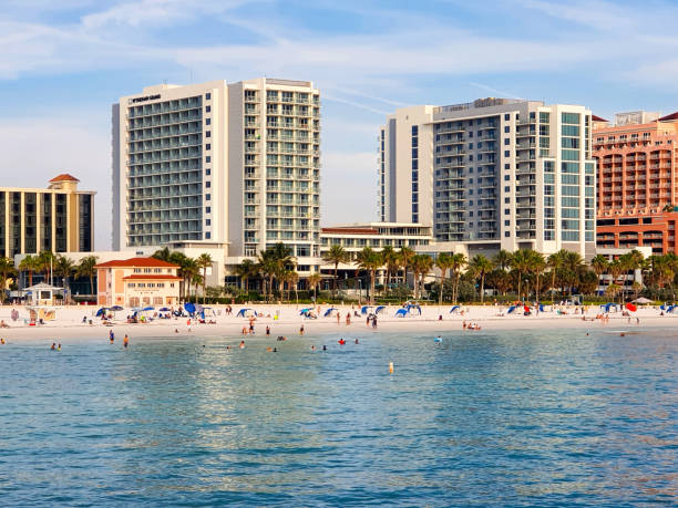 View of the beach and shore in Clearwater, Florida, with reflexions of buildings in the water, people unrecognizable.