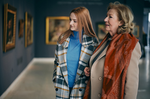 A grandmother and her grandchild enjoying the painting exhibition at gallery.