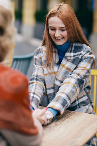 uma avó se conectando com sua neta enquanto estava sentada no café e de mãos dadas. - generation gap multi generation family vertical holding hands - fotografias e filmes do acervo