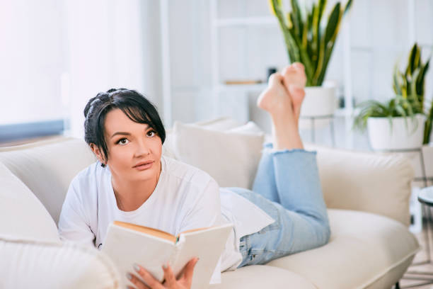 istock beautiful woman on the sofa reading book. Free time, education, self development concept. 1400618578