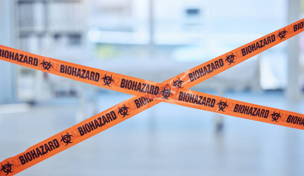 Closeup of biohazard tape blocking prohibited area. Caution tape is used as warning for quarantine hospital room. Toxic empty hospital room in pandemic. Orange security tape blocking hospital room Closeup of biohazard tape blocking prohibited area. Caution tape is used as warning for quarantine hospital room. Toxic empty hospital room in pandemic. Orange security tape blocking hospital room biohazard cleanup stock pictures, royalty-free photos & images