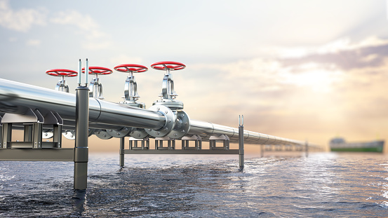 Metal pipeline stretches to horizon in the ocean or sea, sunset blurry background with a cargo vessel in a distance, 3d illustration