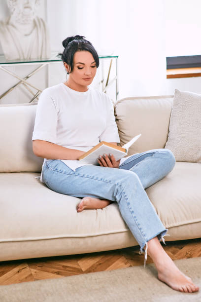 istock beautiful woman on the sofa reading book. Free time, education, self development concept. 1400622396