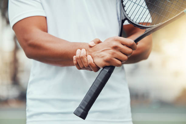 nahaufnahme eines unbekannten indischen tennisspielers, der im gerichtsspiel an einer handgelenksverletzung leidet. ethnischer fit-profi mit schmerzen beim halten und reiben von hand zu spiel. sportlicher mann, der schläger im sportverein hält - handgelenk stock-fotos und bilder