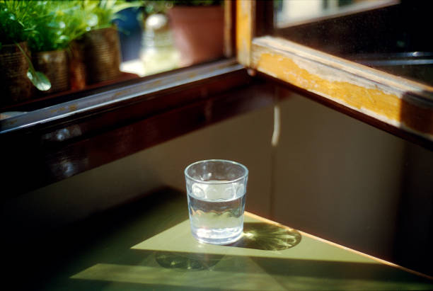 Glass of water lighted by sunset during the golden hour Glass of water on green table near a window, lighted by sunset during the golden hour. golden hour wine stock pictures, royalty-free photos & images